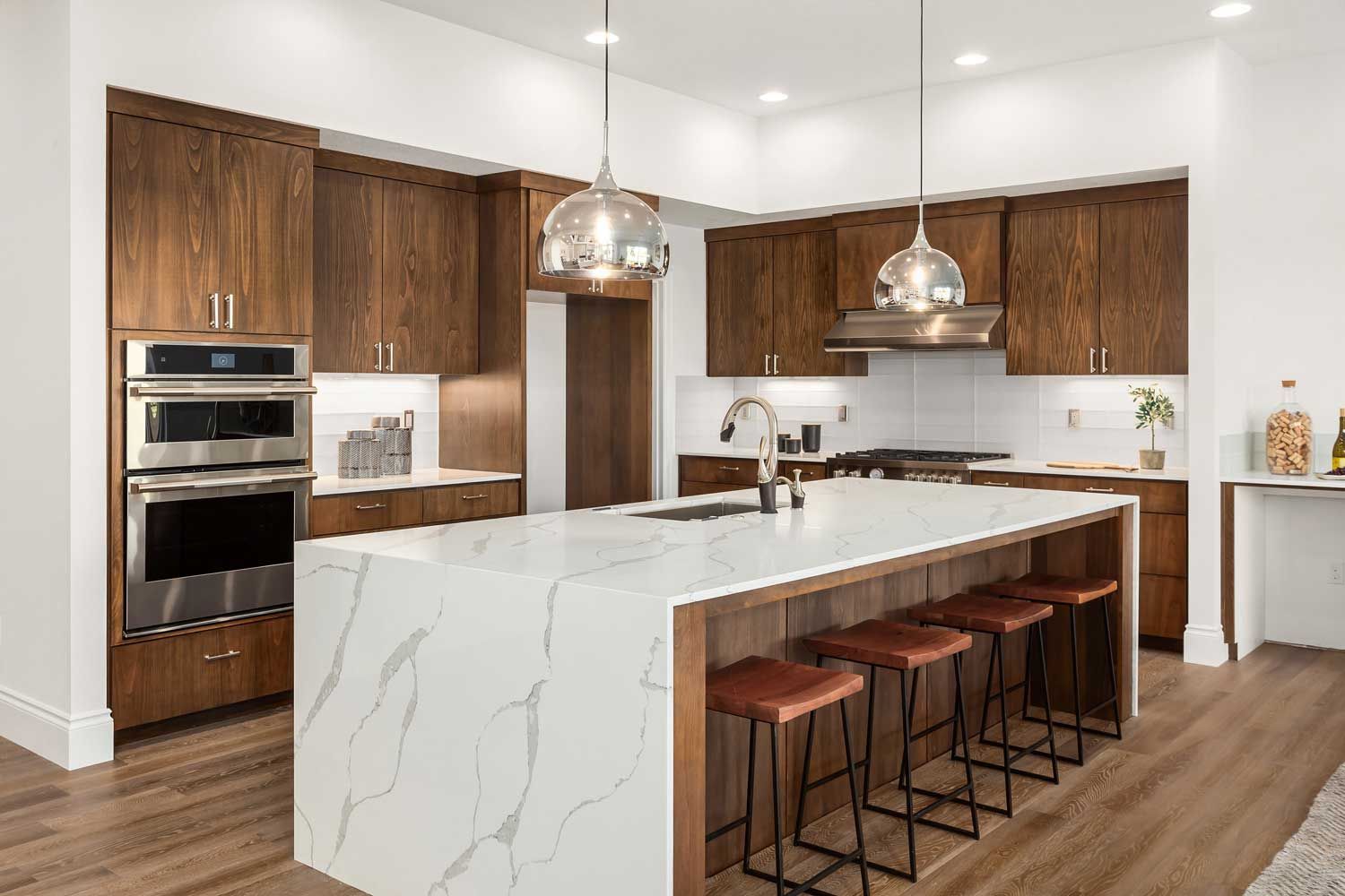A kitchen in a new home with marble counter tops and wooden cabinets.