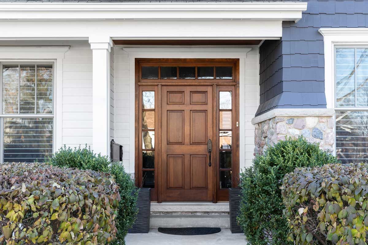 The front door of a house with a wooden door and steps.