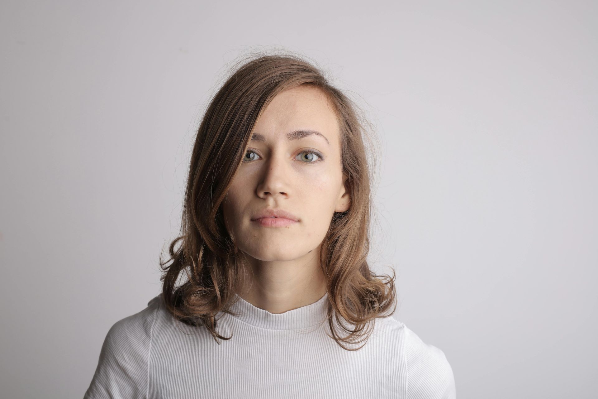 A woman with long hair is wearing a white shirt and looking at the camera.