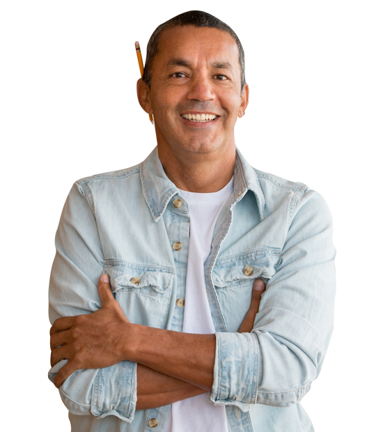 A man in a denim shirt is smiling with his arms crossed