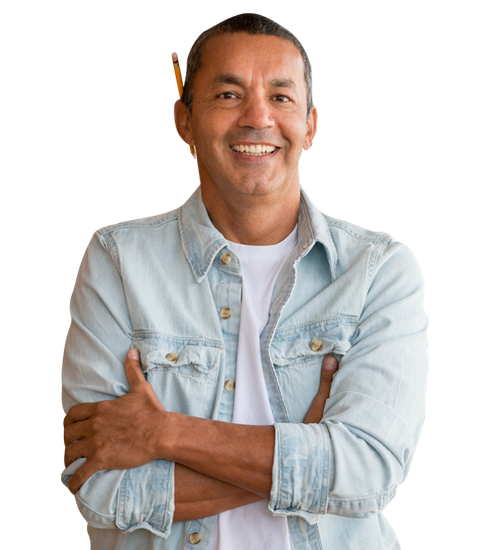 A man in a denim shirt is smiling with his arms crossed