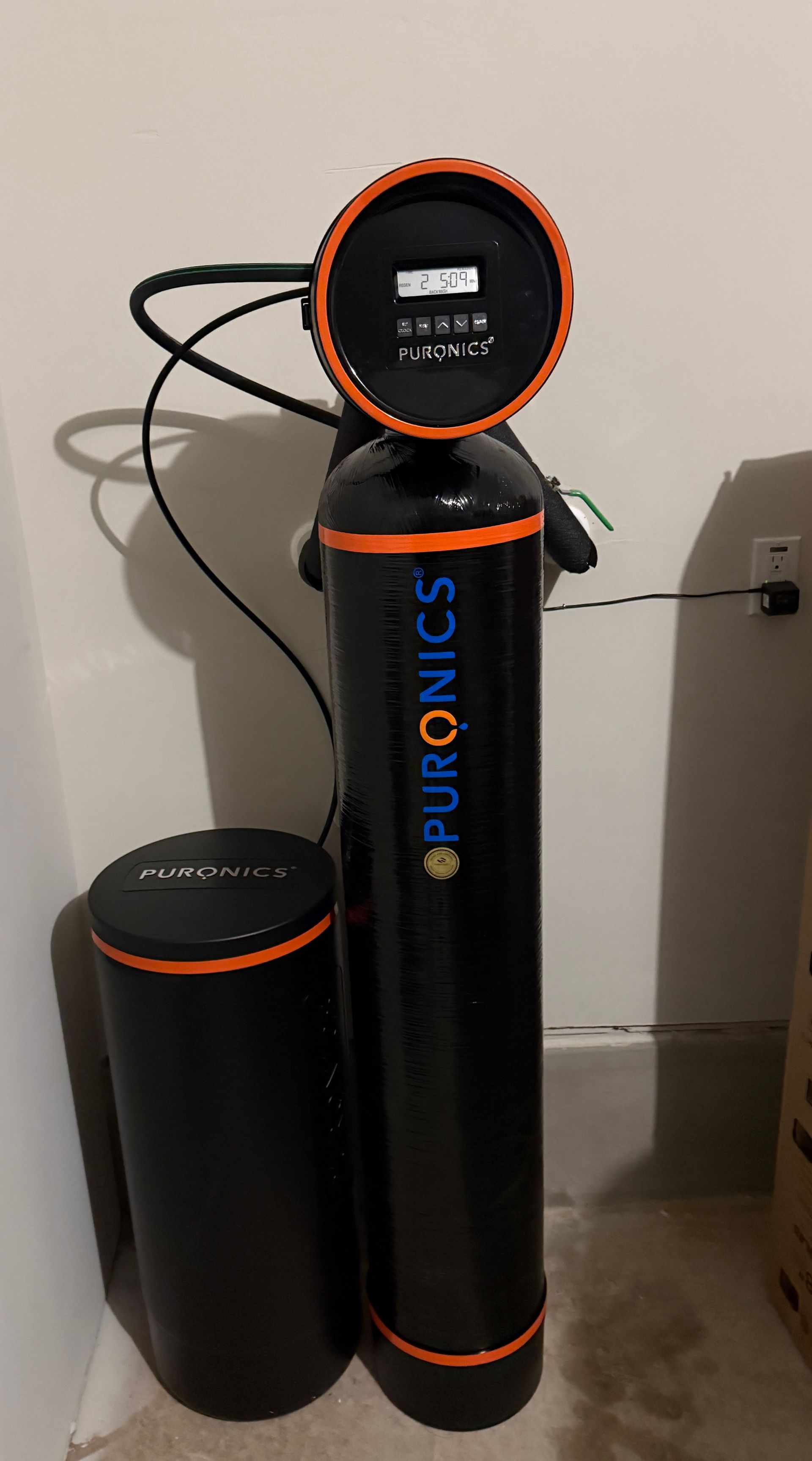 A black water softener is sitting next to a black tank.