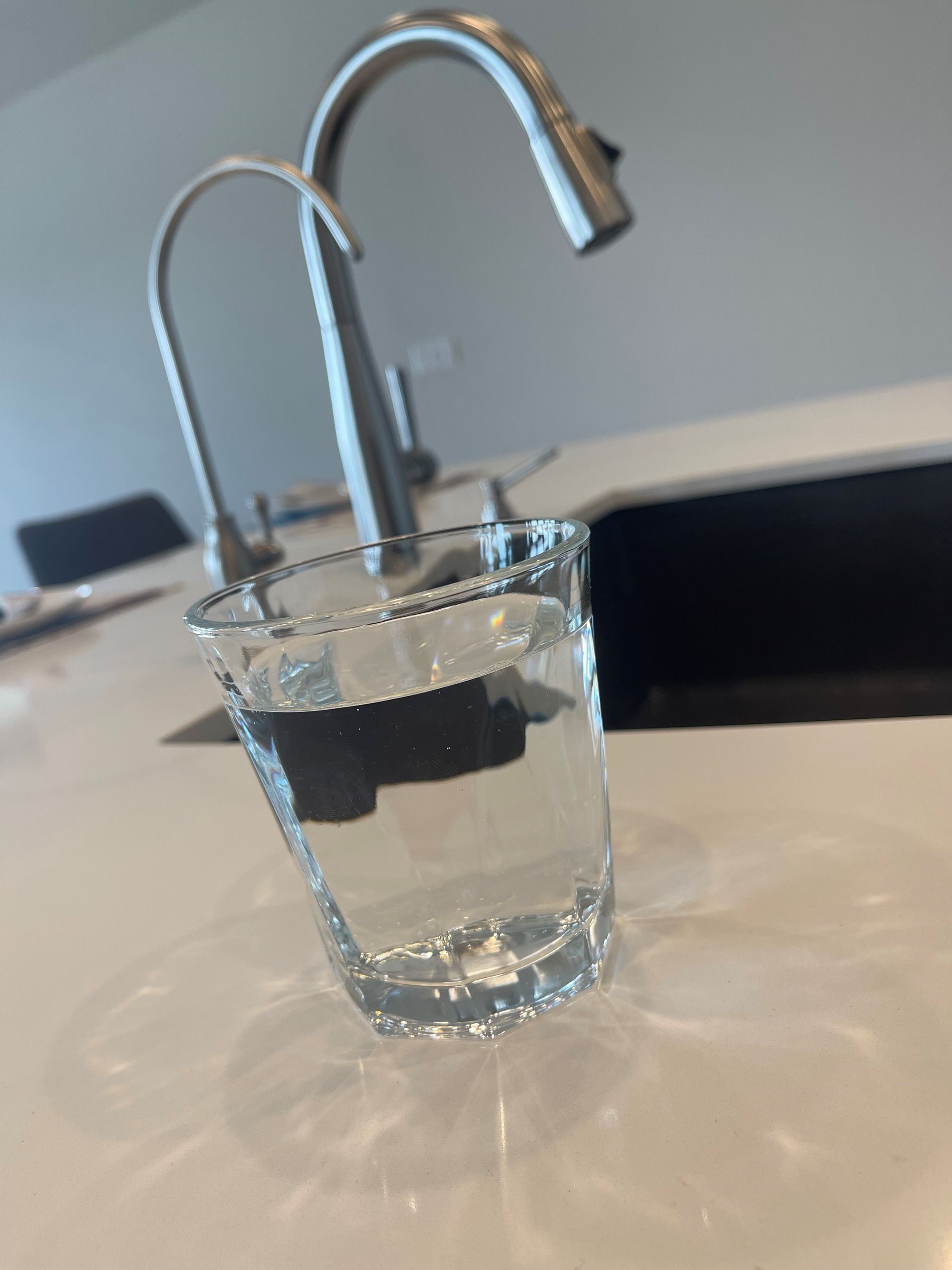 Tetra Water - A person is pouring water into a glass from a faucet.
