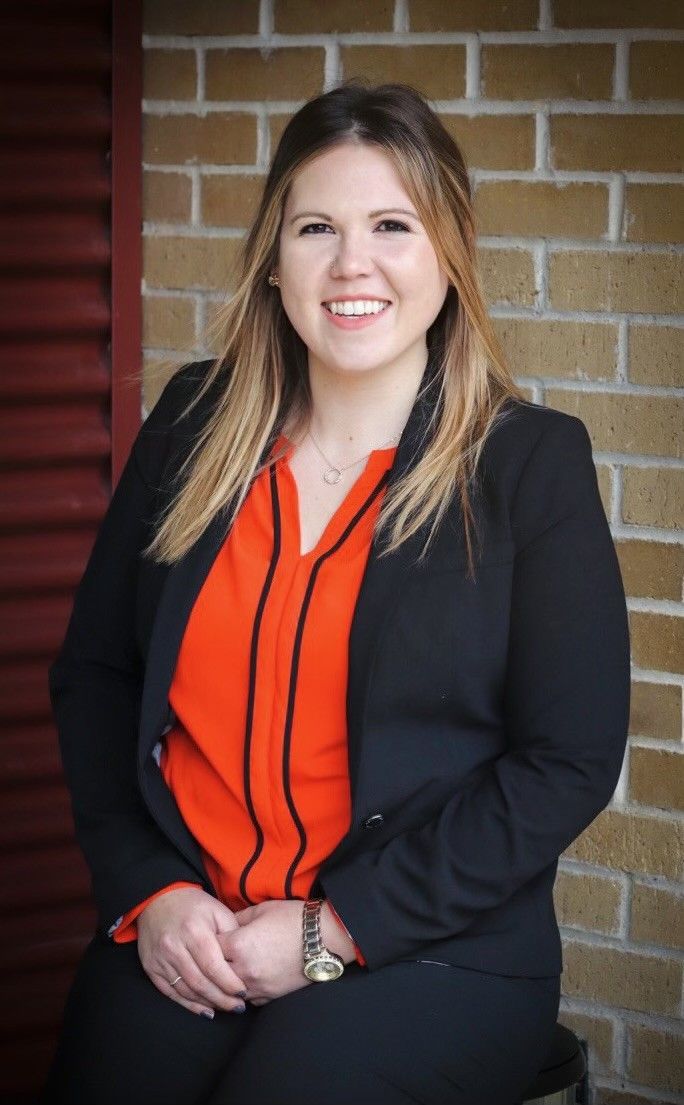 Tetra Water - A woman in a suit and orange shirt is sitting in front of a brick wall.