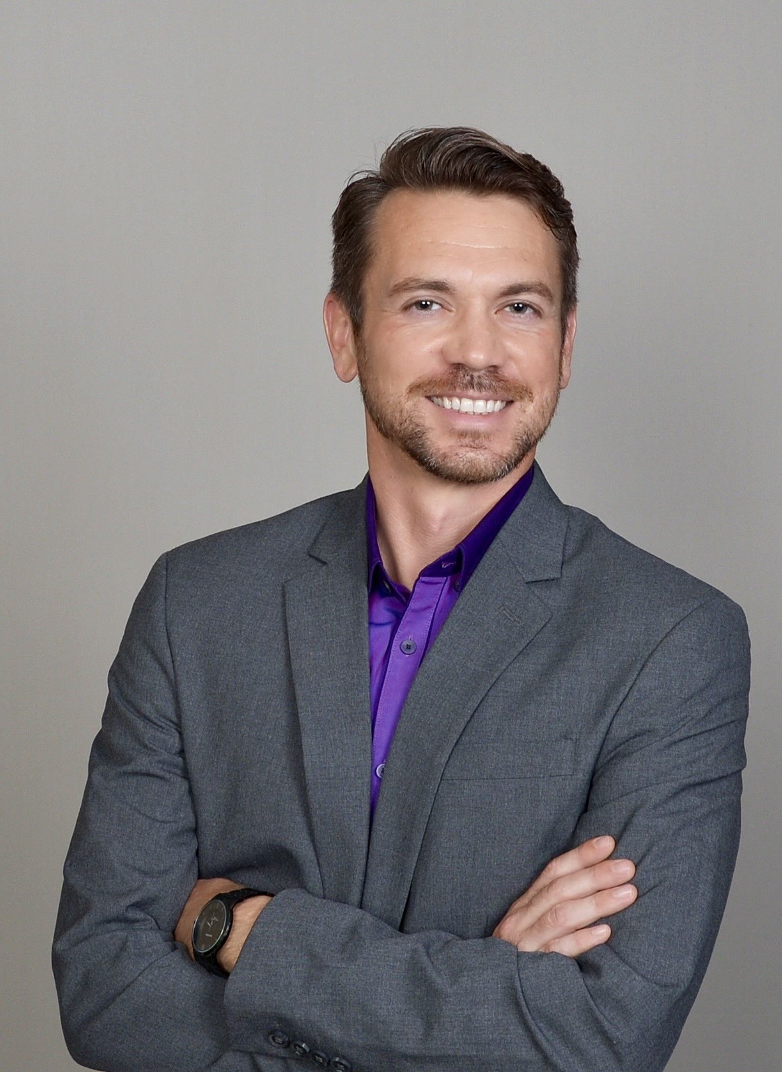 Tetra Water - A man in a suit and purple shirt is standing with his arms crossed.