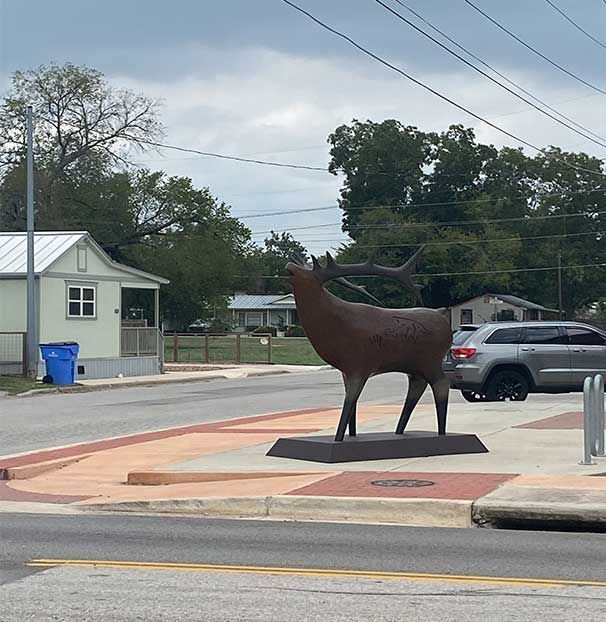 A statue of a deer is in the middle of a street