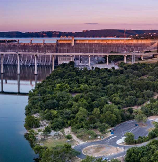 An aerial view of a bridge over a body of water surrounded by trees.