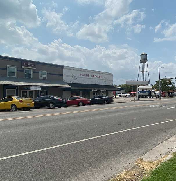 A row of cars are parked on the side of the road in front of a building.