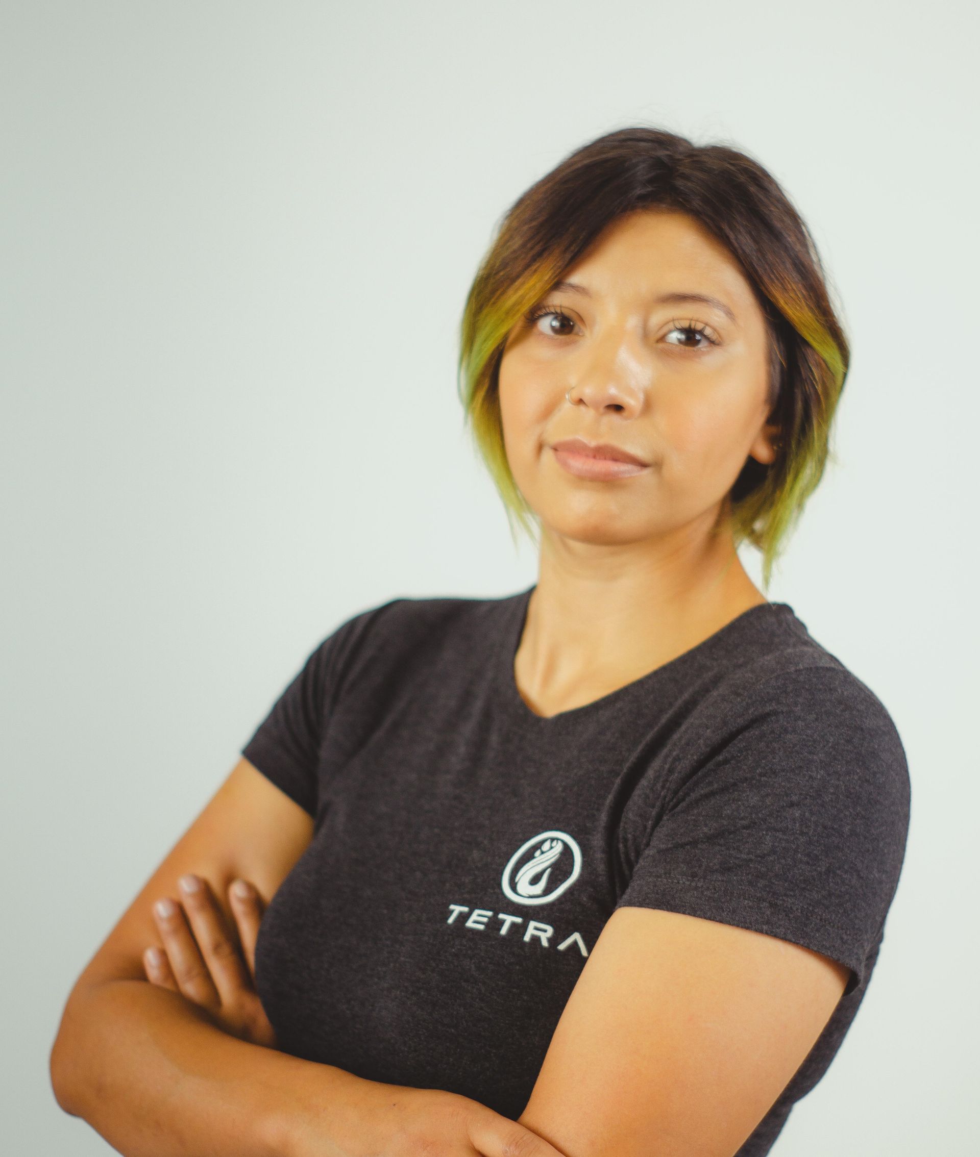 Woman with crossed arms, wearing a gray shirt with