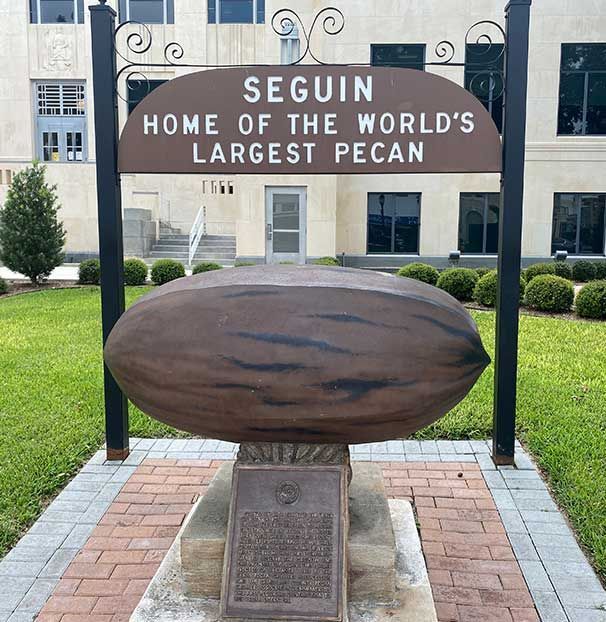 A sign that says seguin home of the world 's largest pecan