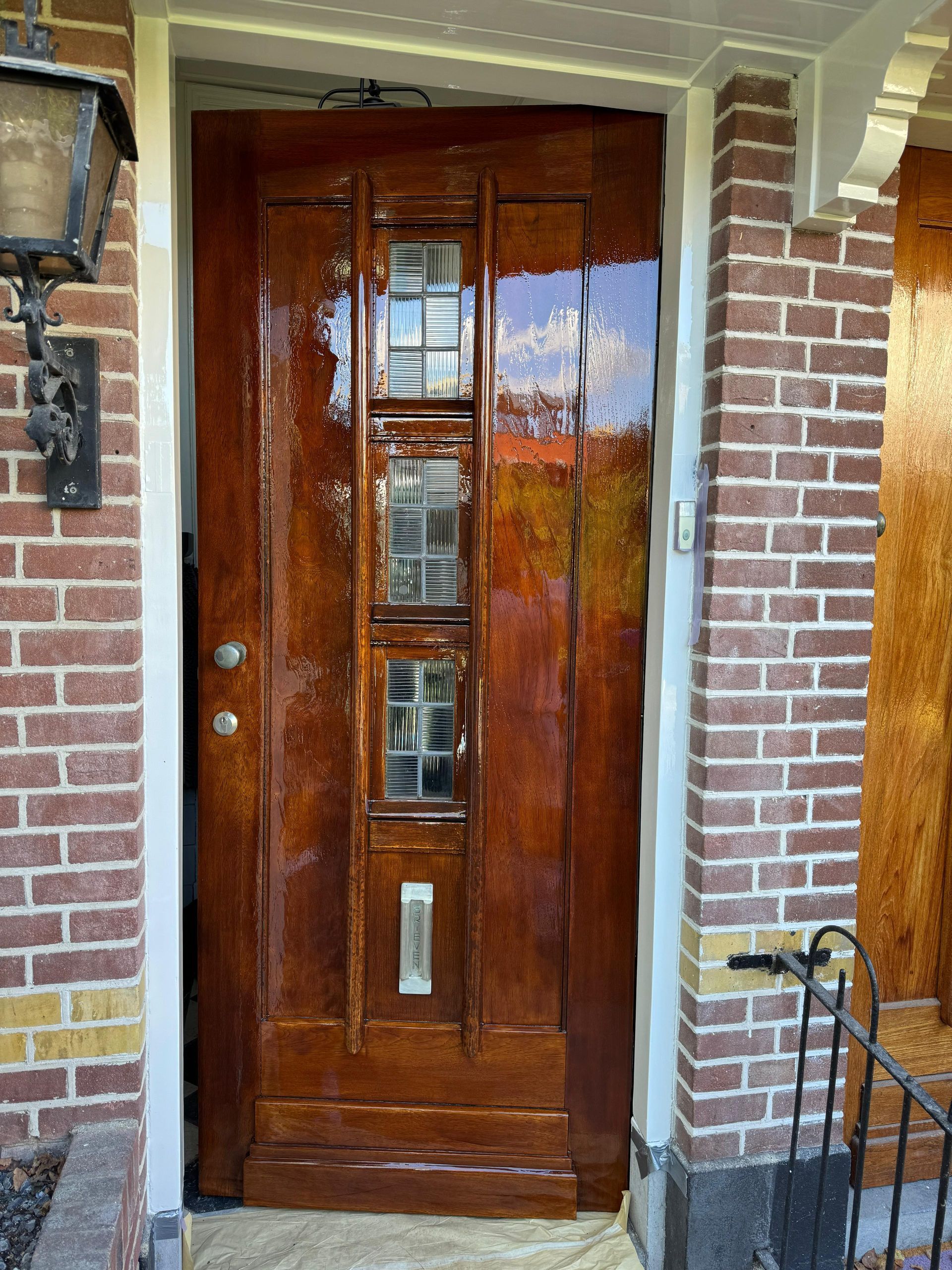 Een houten deur staat voor een bakstenen gebouw.