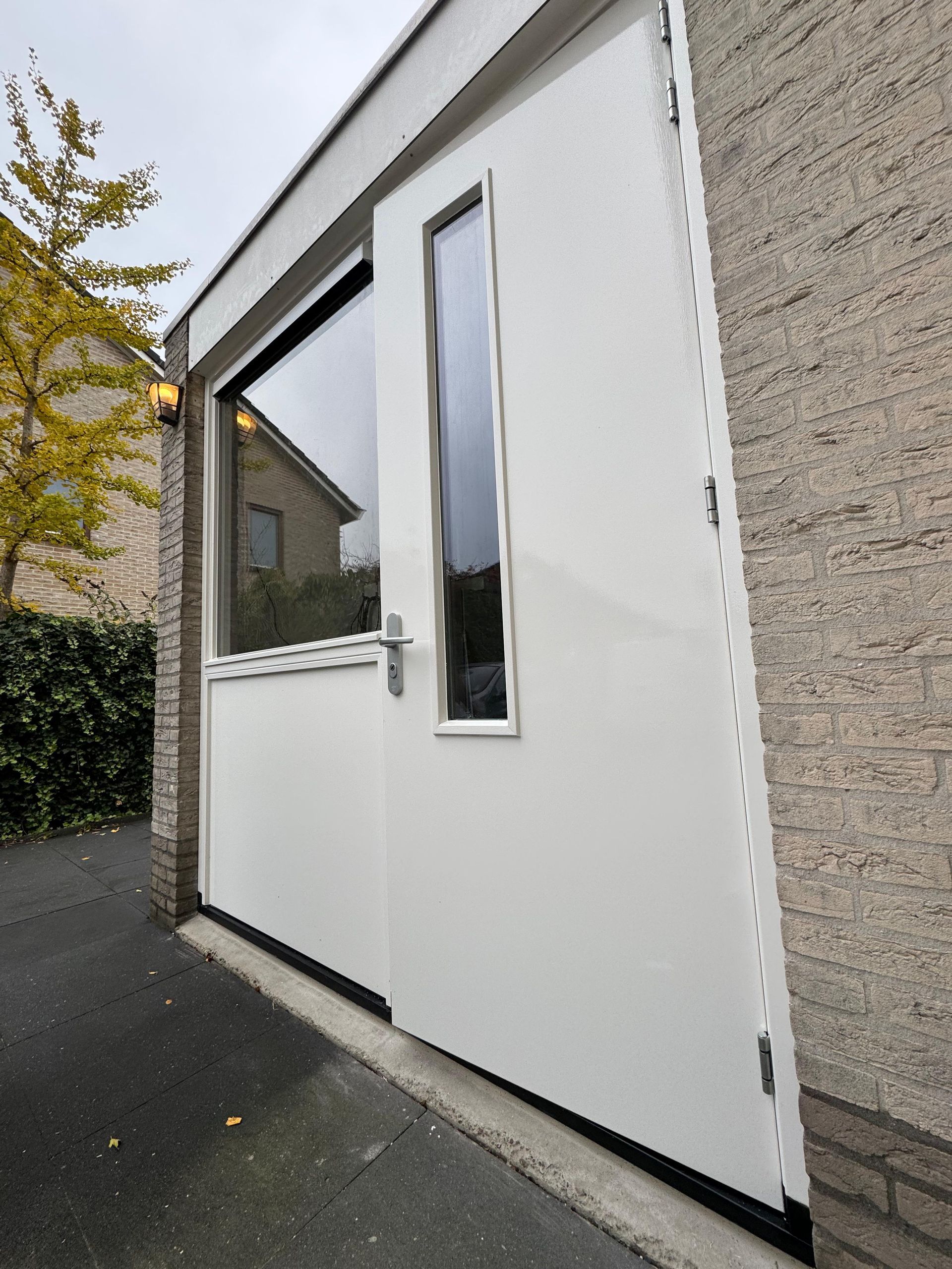 Een witte deur met een raam aan de zijkant van een gebouw