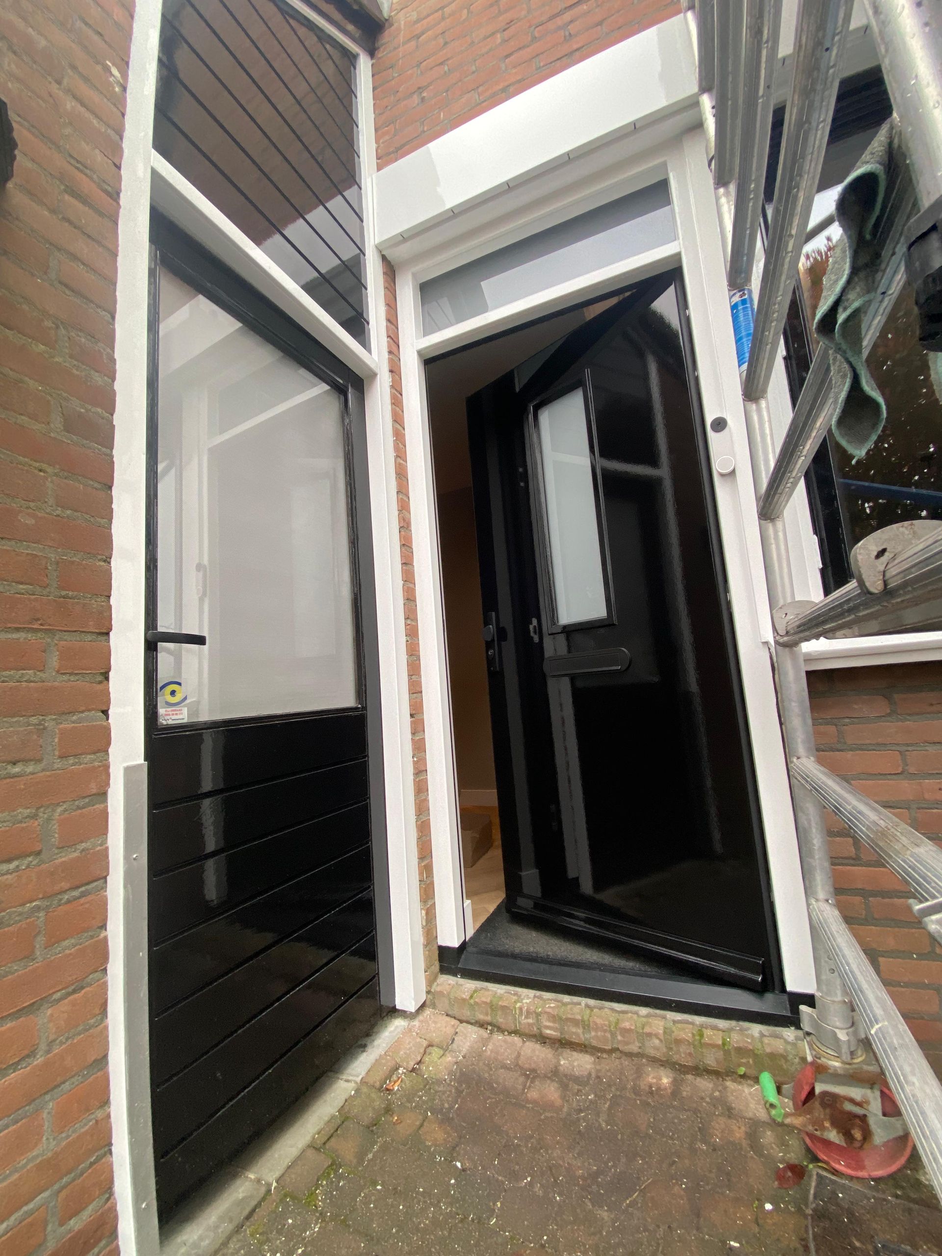 Een zwarte deur zit aan de zijkant van een bakstenen gebouw.