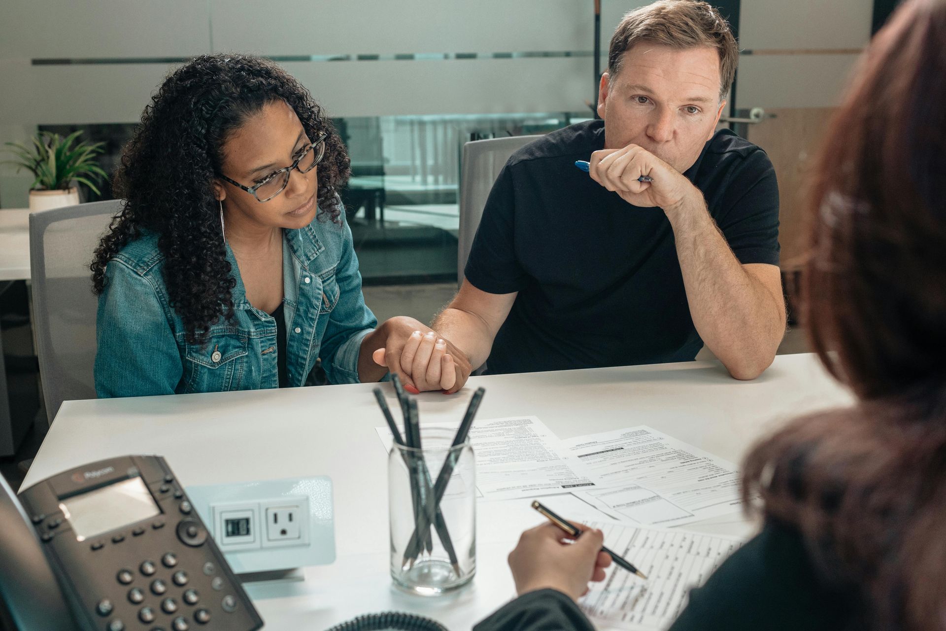 A man and a woman are sitting at a table talking to a woman.