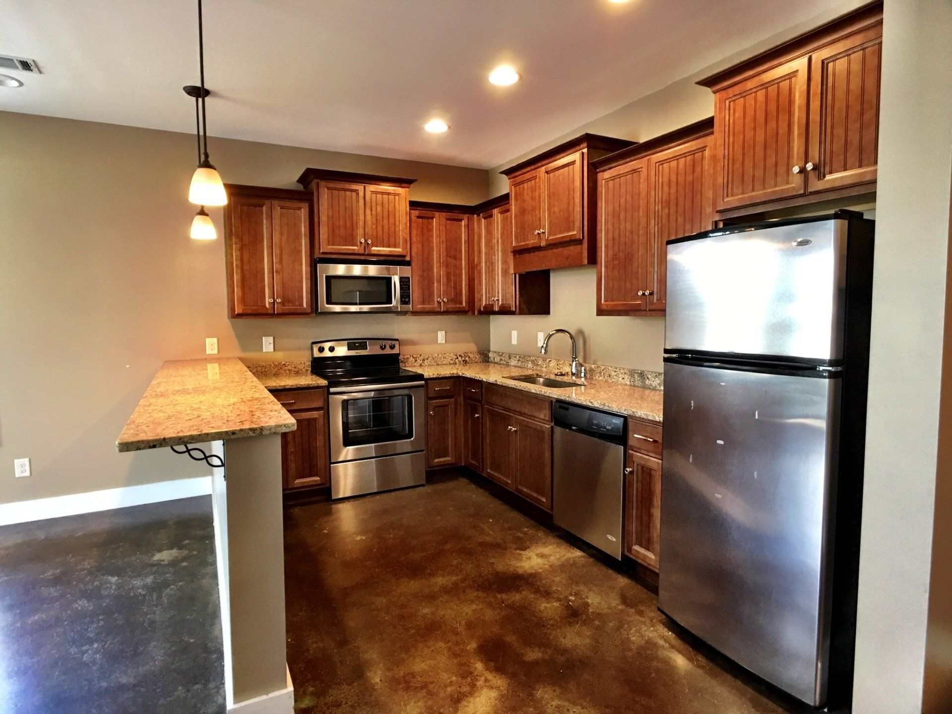 A large kitchen with bar, granite counter tops, and stainless steel appliances