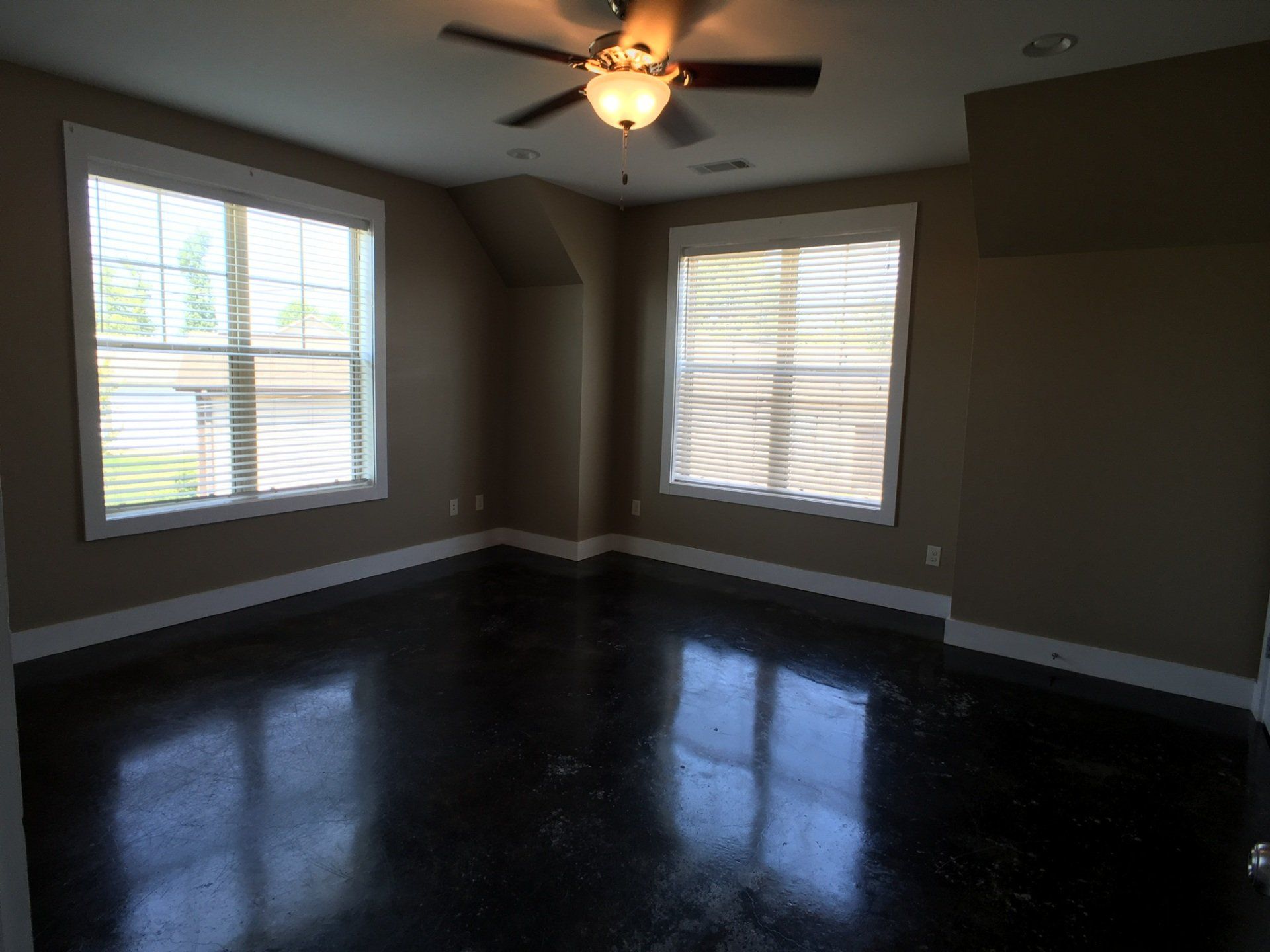 A living room with large windows and ceiling fan