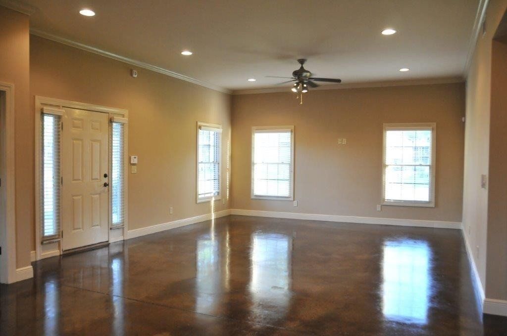 A large living room with big windows and ceiling fan