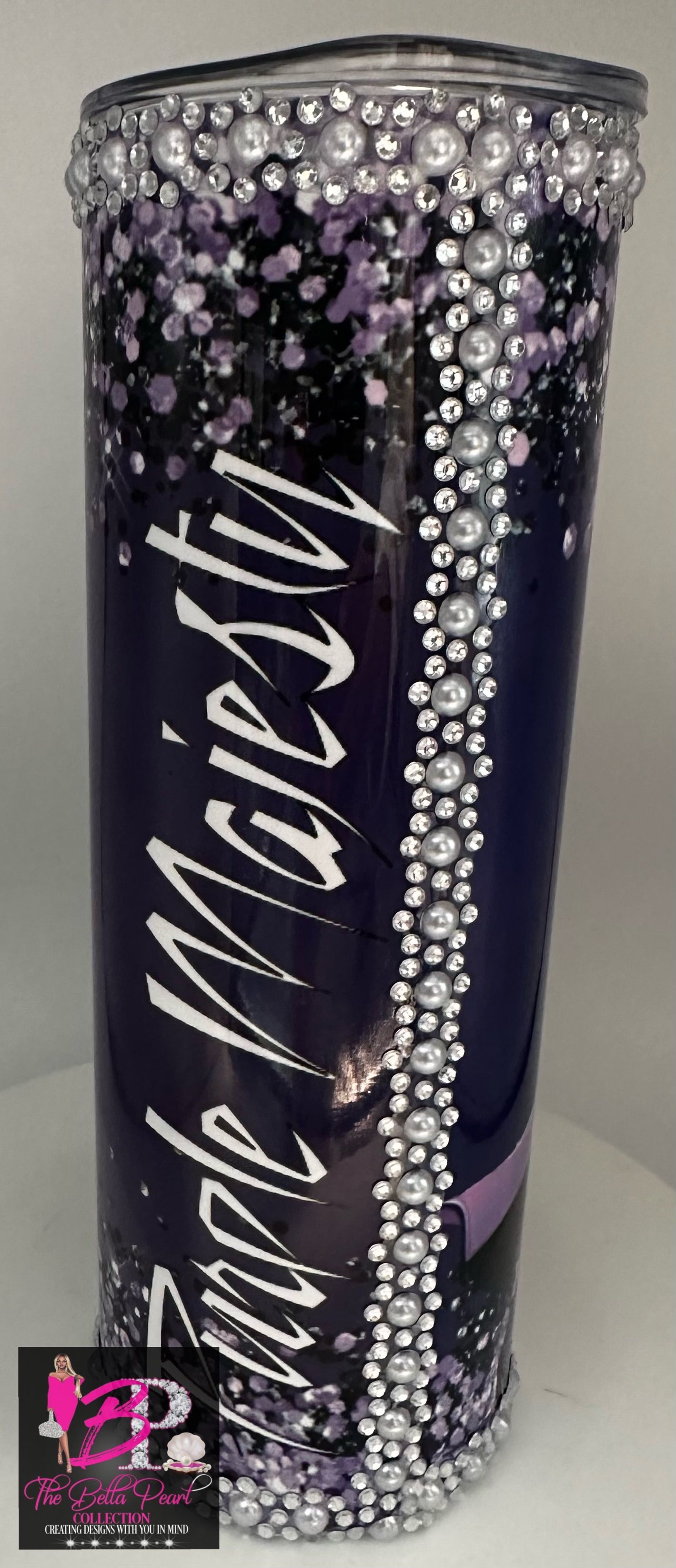 A purple tumbler with rhinestones and glitter on it is sitting on a table.