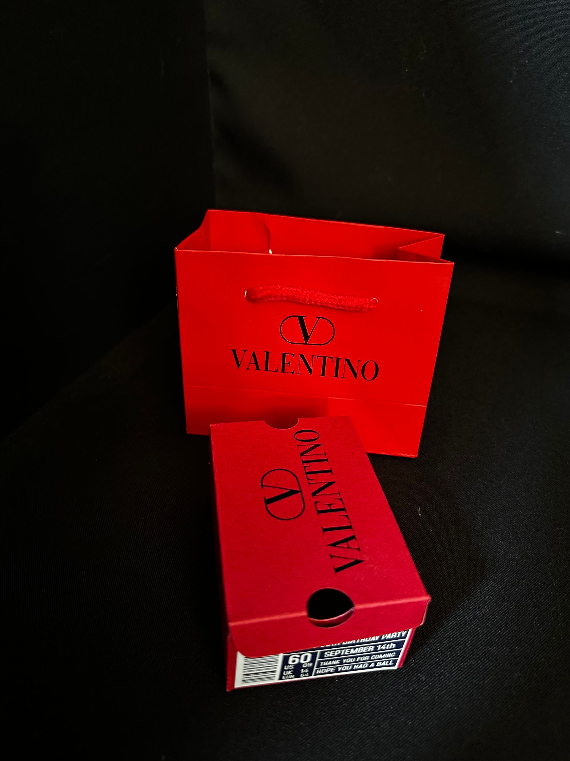 A red valentino favor bag sits next to a red favor shoebox