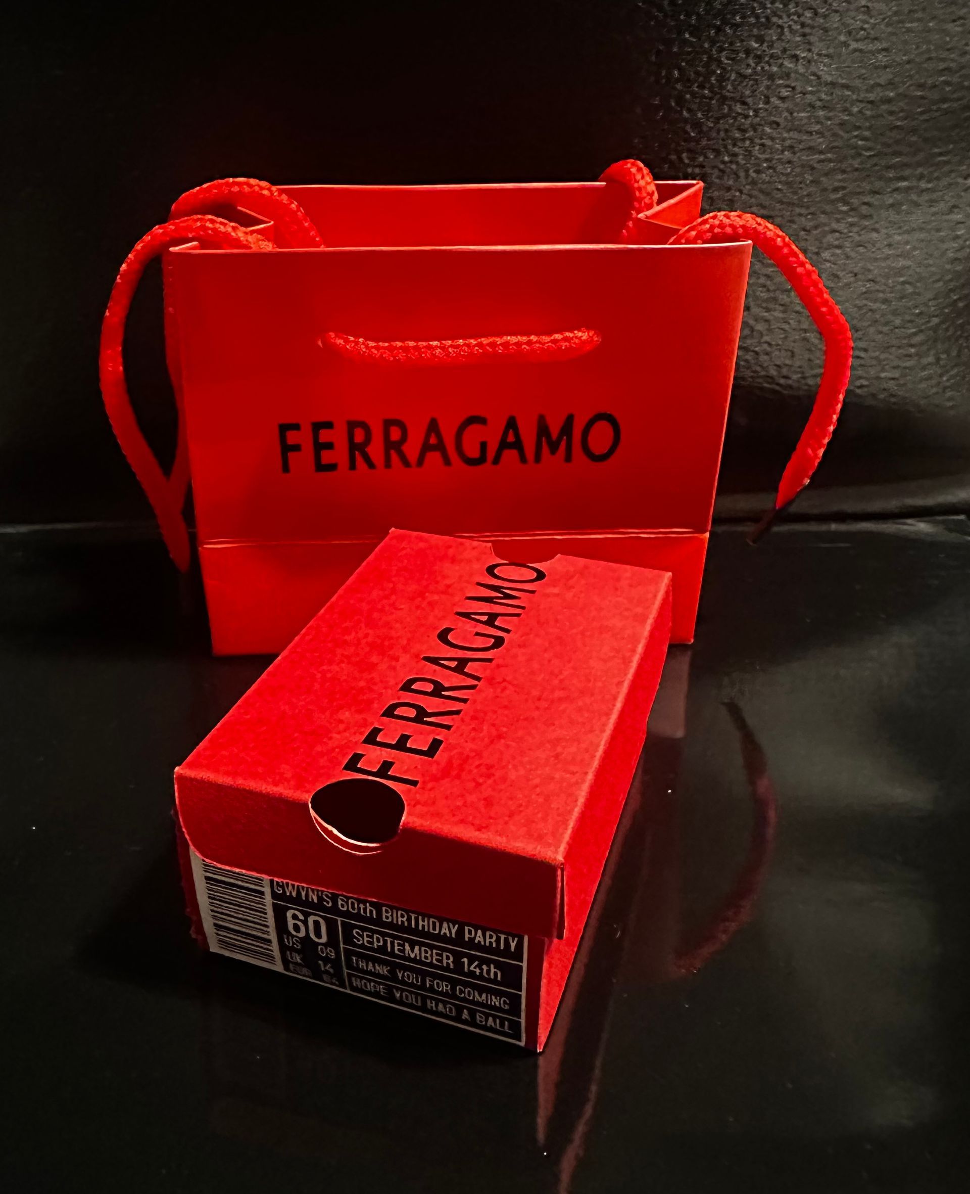 A red ferragamo favor bag sits next to a red favor shoebox