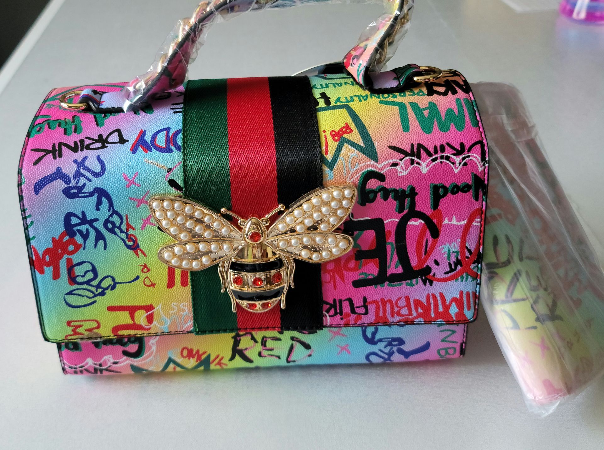 A colorful purse with a bee on it