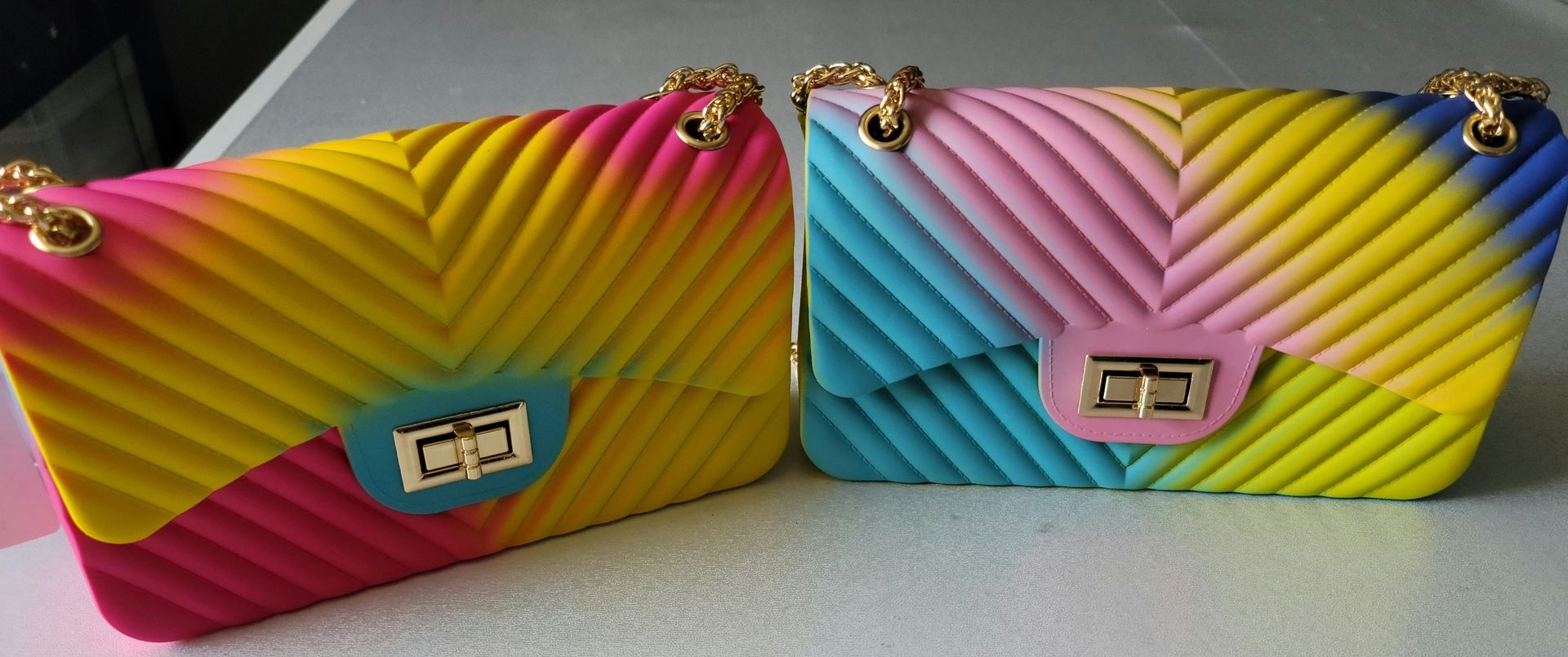 Two colorful handbags are sitting next to each other on a table.