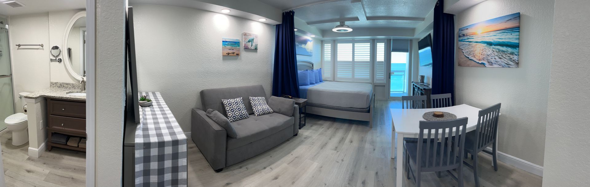 Small studio apartment with a living area, bed, and dining table, with a bathroom on the left.