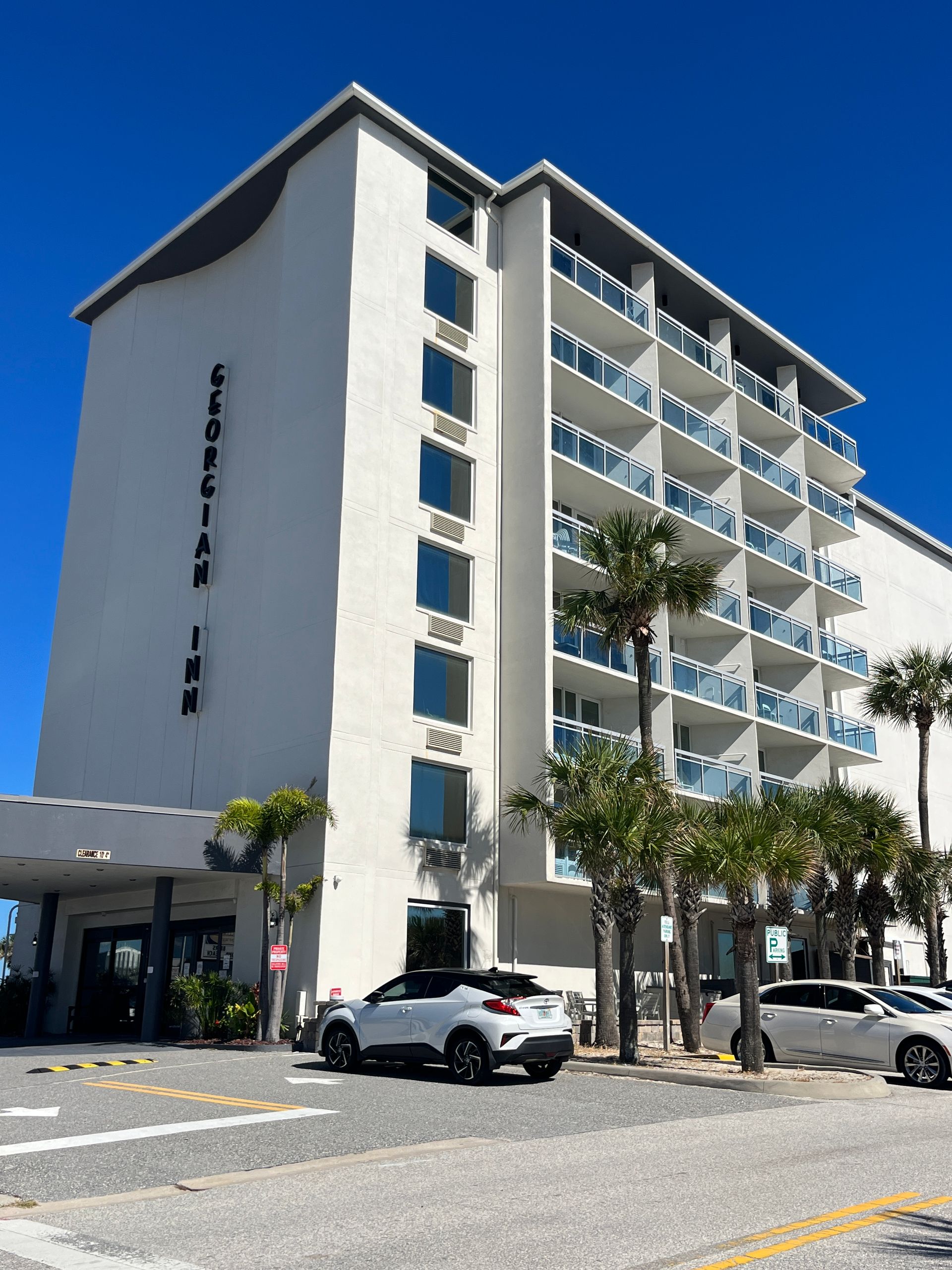 Floridian Inn hotel, white exterior, palm trees, parked cars, clear blue sky.