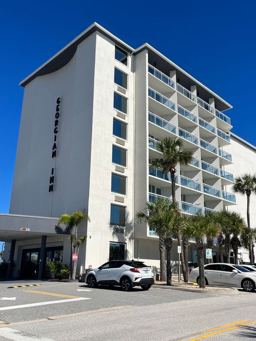 The Georgian Inn hotel exterior with a white exterior, blue sky, and parked cars.