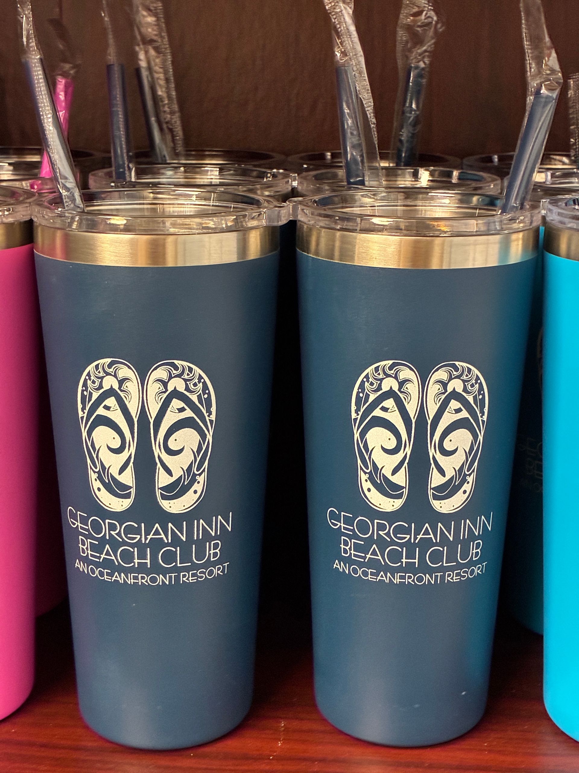 Two blue tumblers with beach-themed logo and straws; product display.