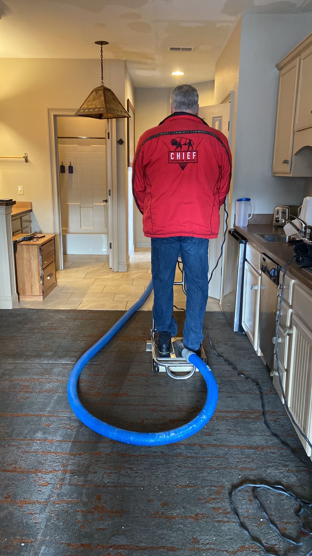 A woman is standing in a kitchen next to a bucket of water.