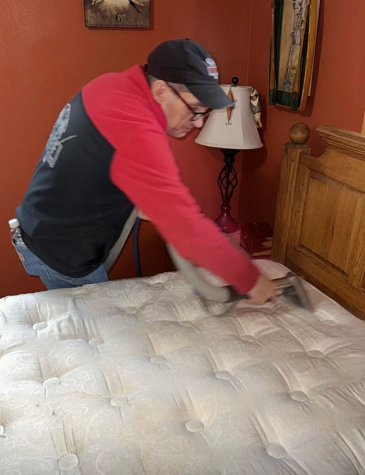 A person is cleaning a couch with a vacuum cleaner.