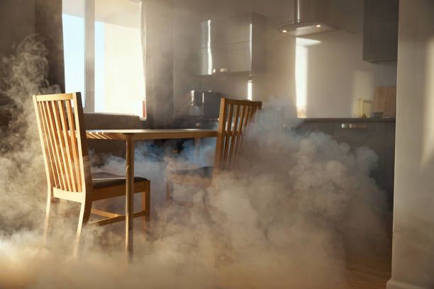 A kitchen with smoke coming out of the ceiling and a table and chairs.