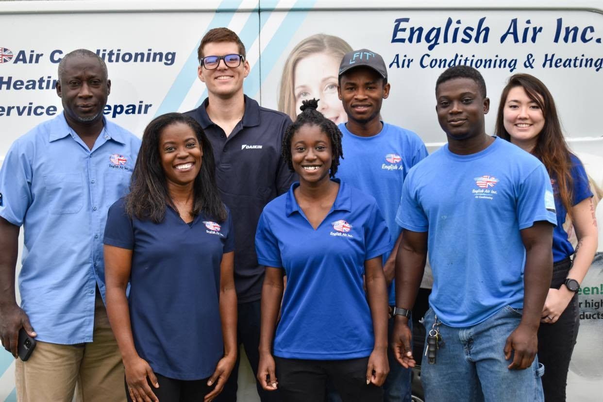 Five employees in blue shirts posing in front of an English Air Inc. sign.