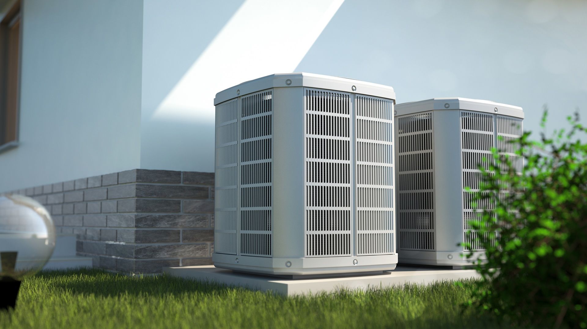 Two outdoor HVAC units beside a house wall on a sunny lawn