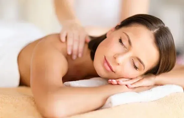 A person with closed eyes rests peacefully on a spa table while receiving a professional back massage.