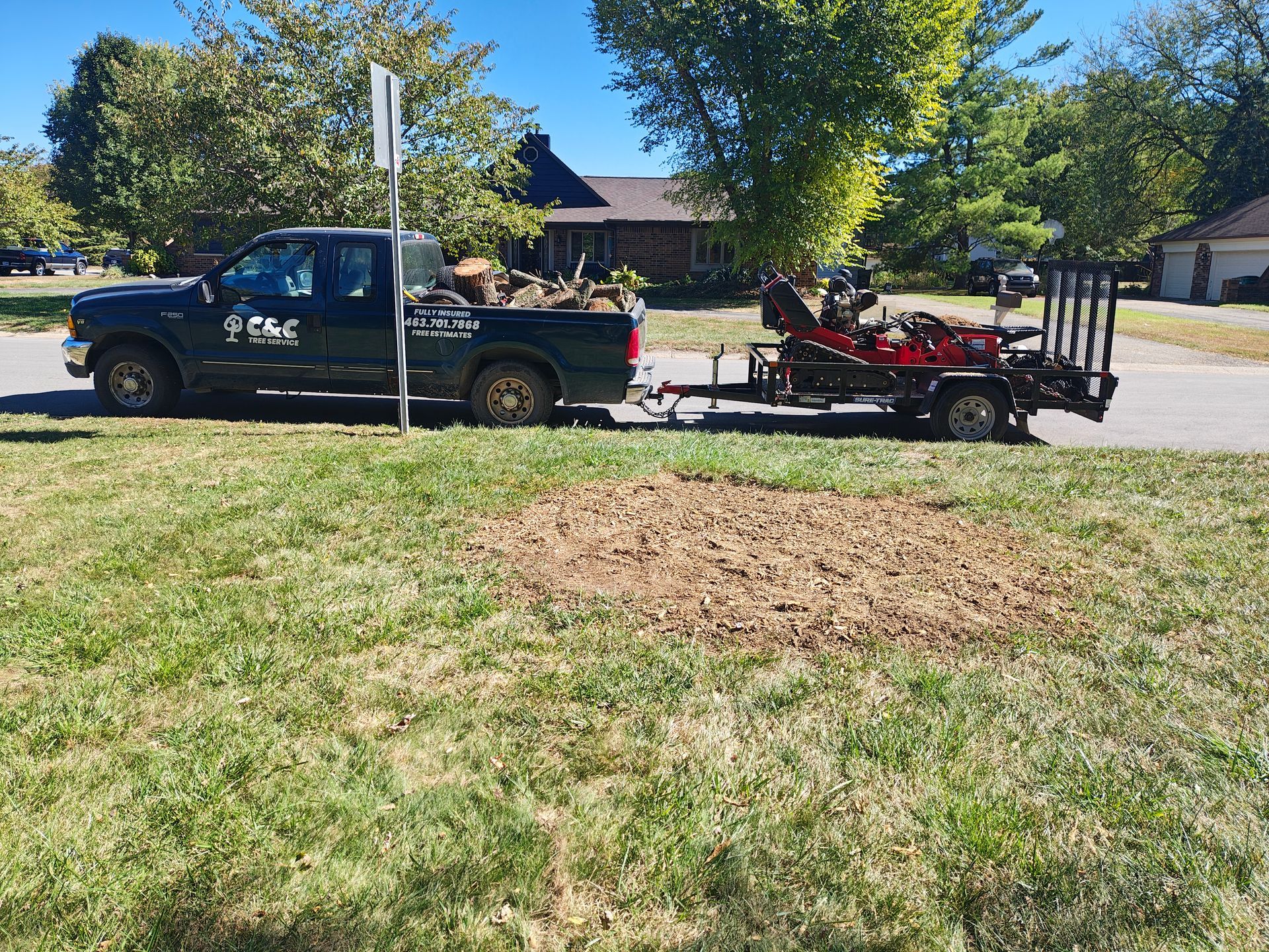 Yellow stump grinder grinding a tree stump in green grass.