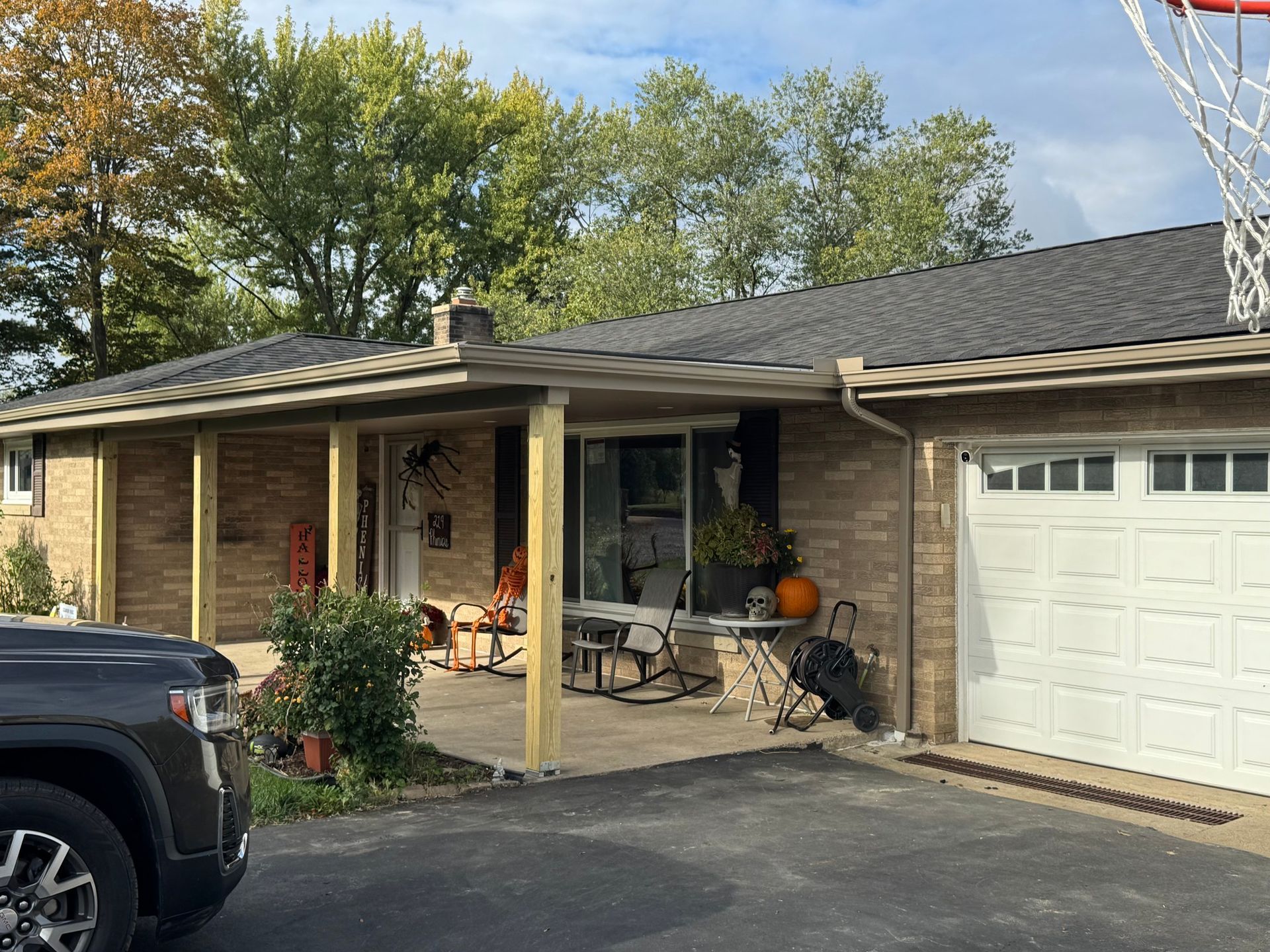 House with a covered porch and garage. A dark SUV is parked in front.