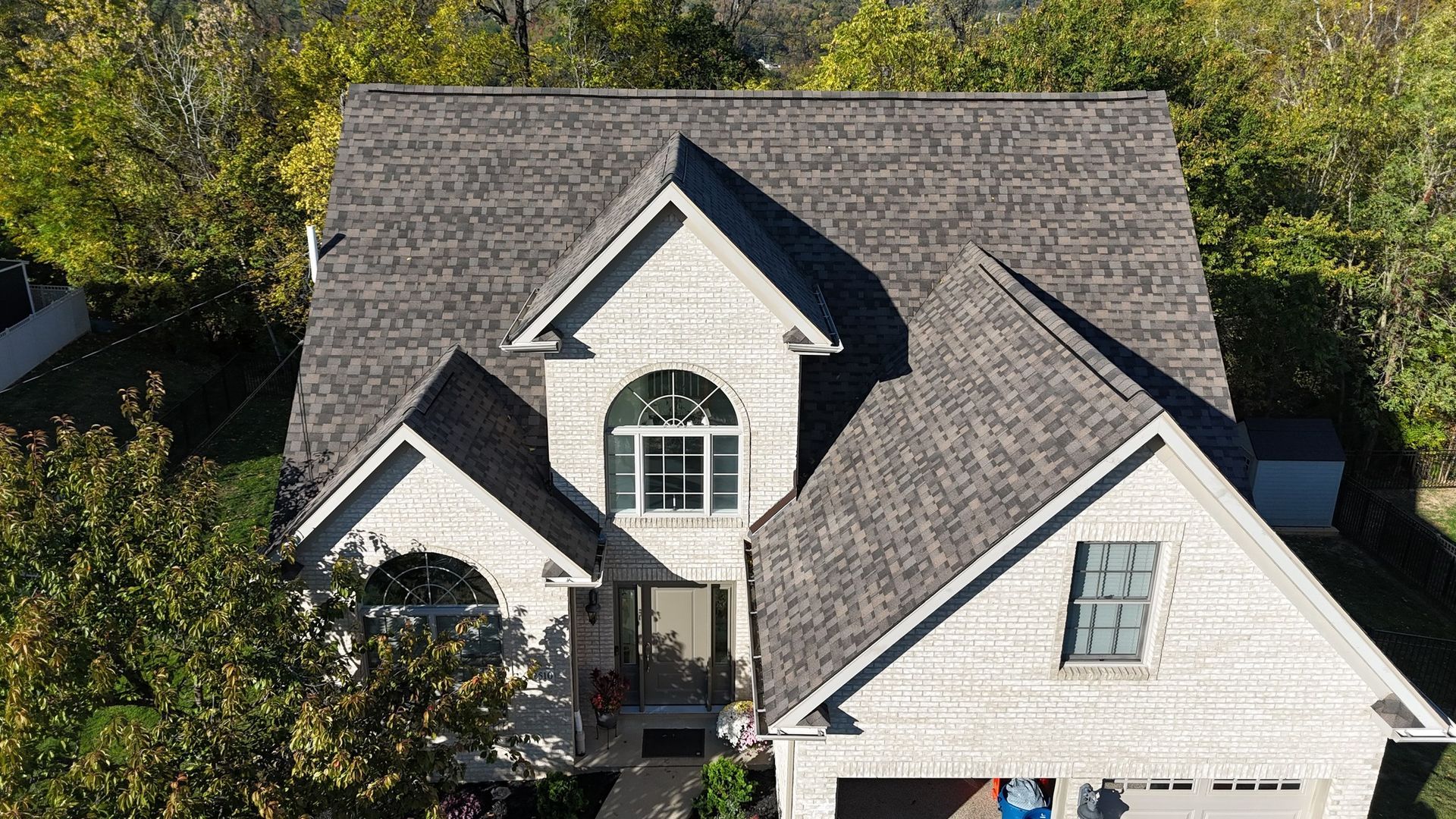 Gray roofed house with arched window, surrounded by trees.