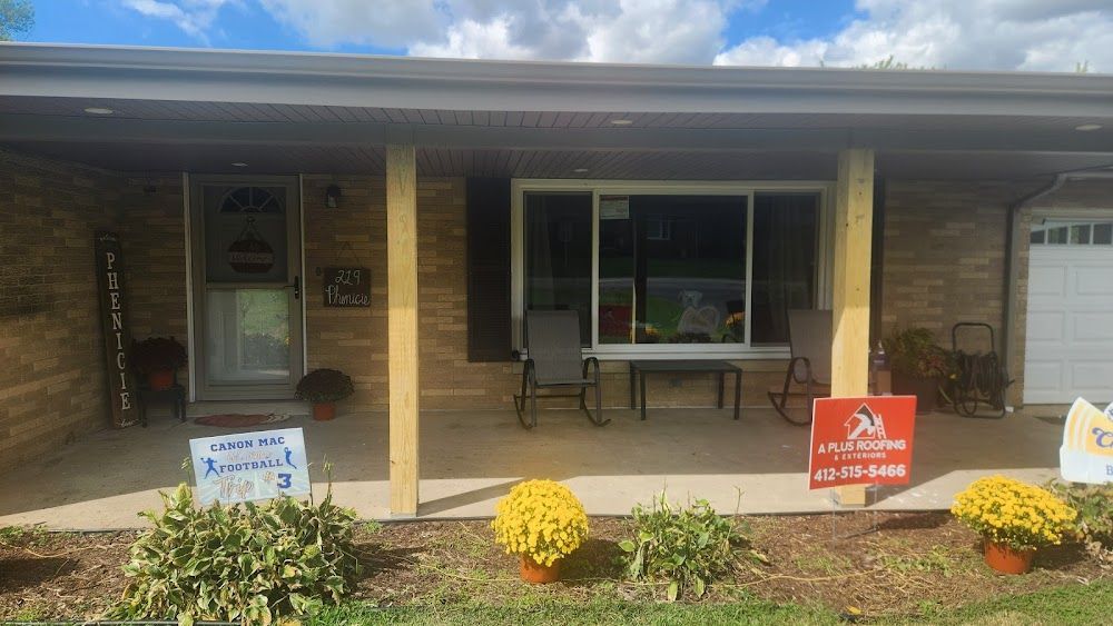 Front porch of a house with support beams, chairs, and potted flowers. 