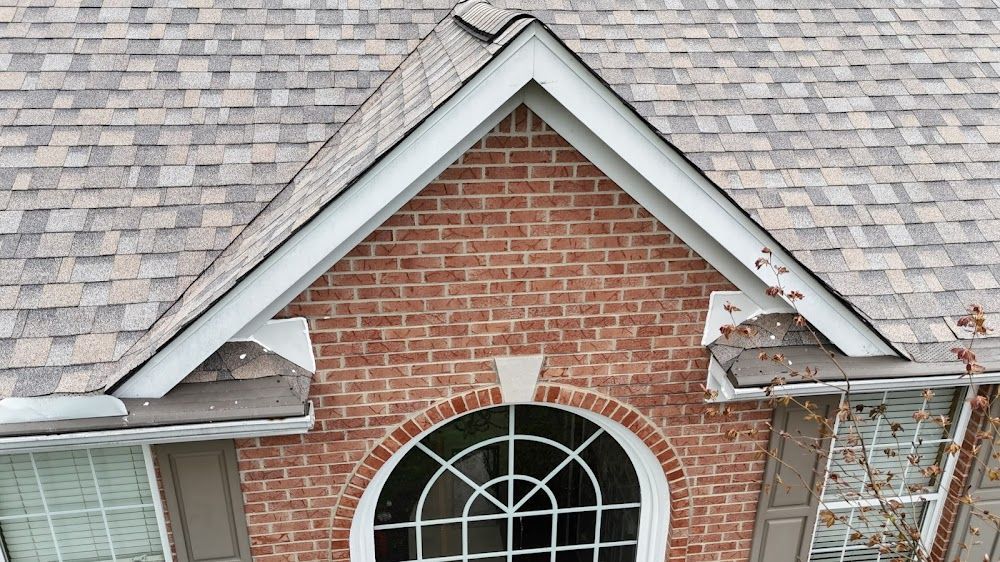 Brick house with a gable roof, arched window, and gray shingles.