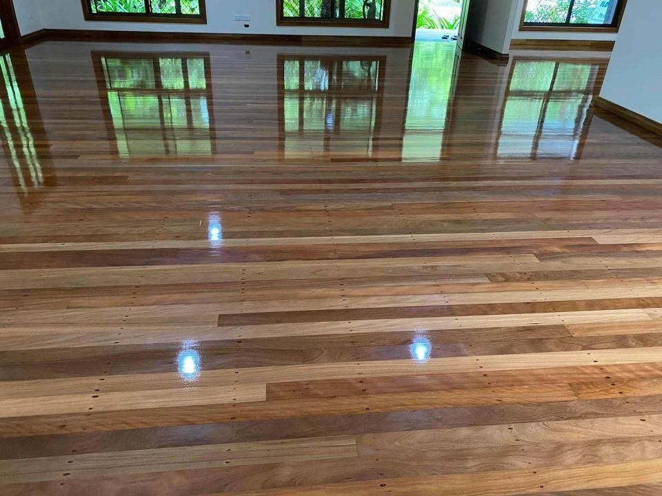 A Large Empty Room With A Wooden Floor And Windows — AJ's Cleaning & Floor Sanding In Woree, QLD