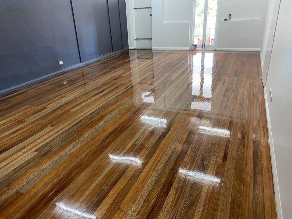 A Living Room With A Shiny Wooden Floor And A Door — AJ's Cleaning & Floor Sanding In Woree, QLD