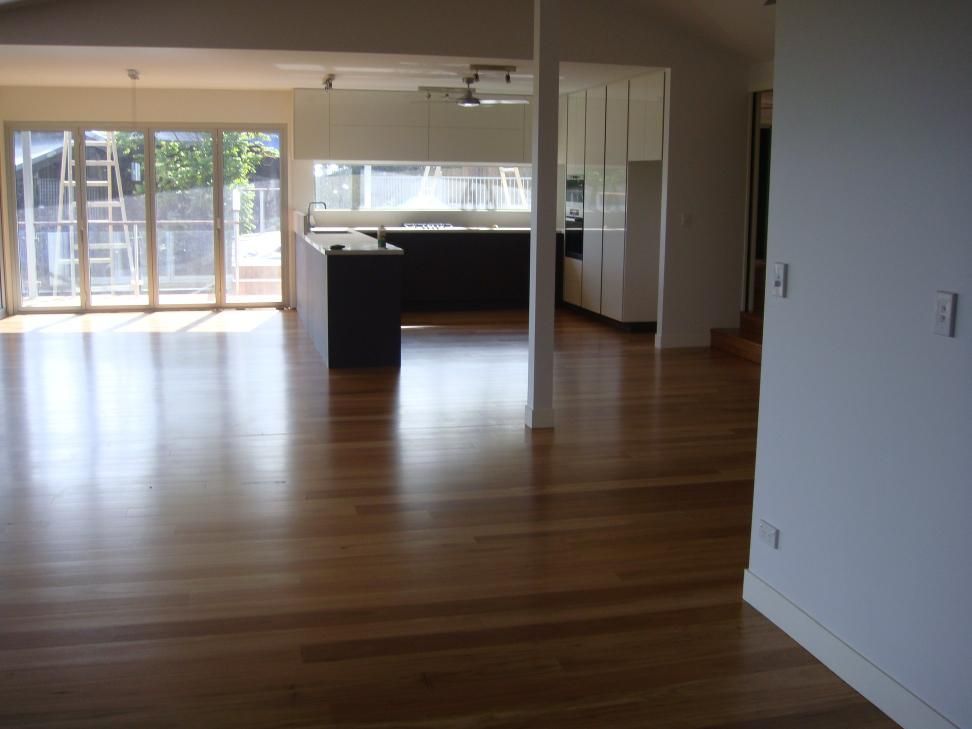A Large Empty Room With Hardwood Floors And White Walls — AJ's Cleaning & Floor Sanding In Woree, QLD