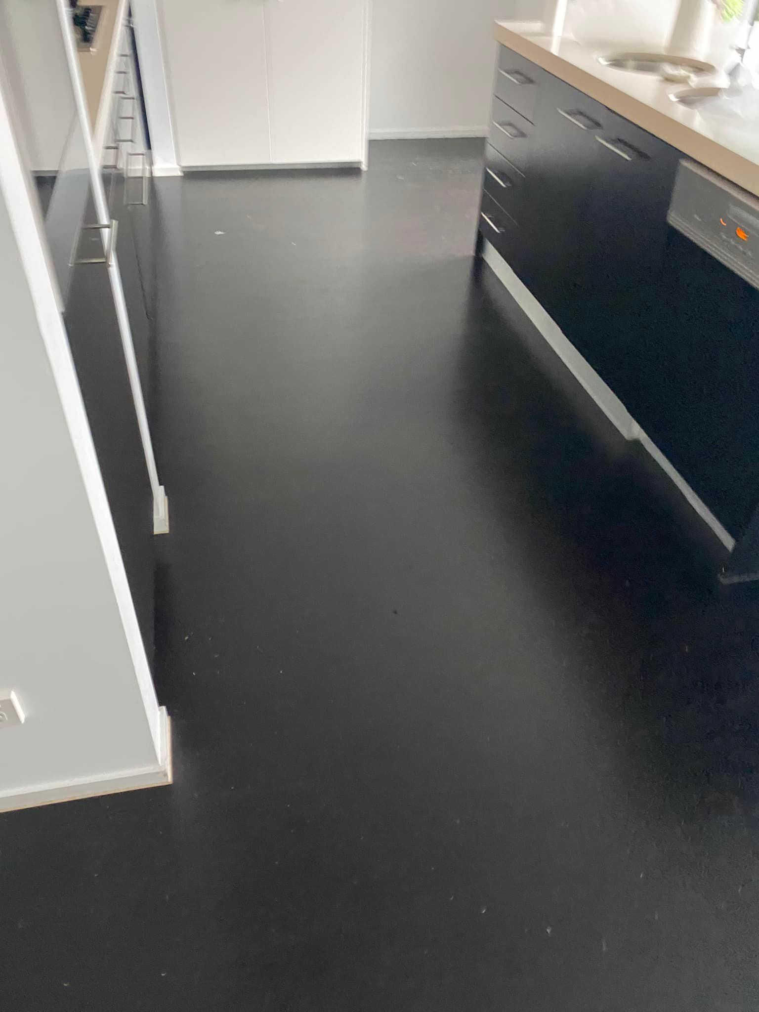 A Kitchen With A Black Floor And Black Cabinets — AJ's Cleaning & Floor Sanding In Woree, QLD