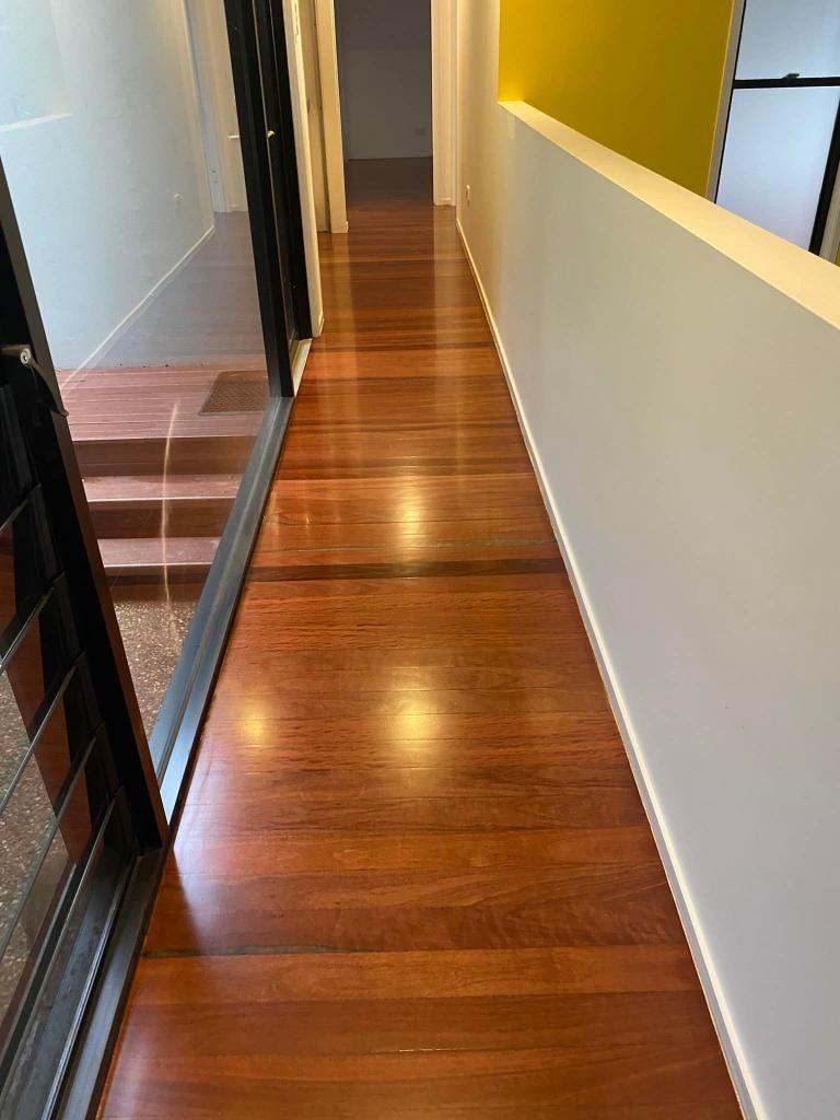 A Long Hallway With Wooden Floors And A Yellow Wall — AJ's Cleaning & Floor Sanding In Woree, QLD