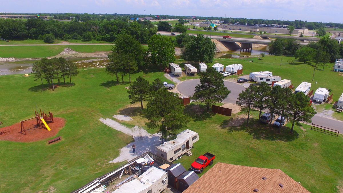 An aerial view of a park with a lot of rvs parked in the grass.