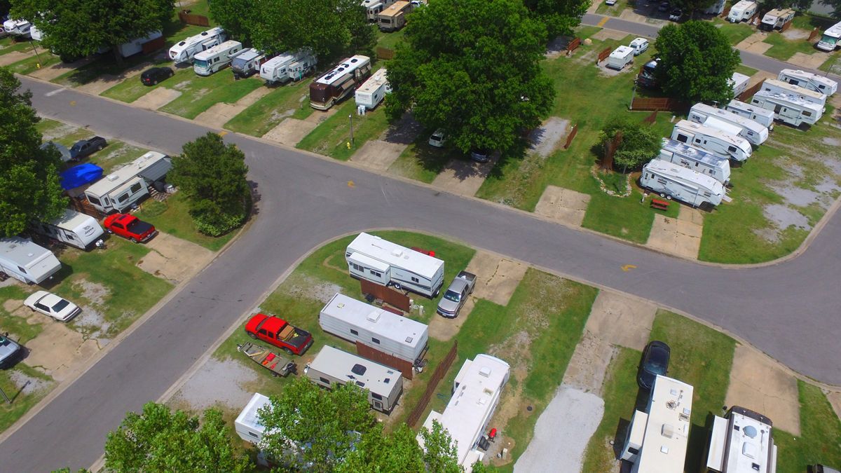 An aerial view of a campground with a lot of rvs parked in the grass.
