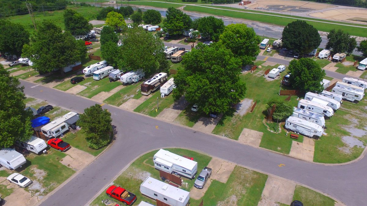 An aerial view of a campground with a lot of rvs parked in the grass.