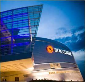 The bok center is lit up at night with a blue sky in the background.